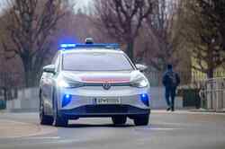 Ein VW Polizeiwagen fährt mit Blaulicht auf der Straße.