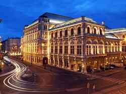 Ein Foto der beleuchteten Wiener Staatsoper bei Nacht.